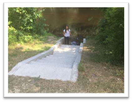 A woman stands at the end of concrete stairs leading to a public canoe access to the Lamprey River. Pictures courtesy of Jim MacCartney, NPS, Dick Lord and Suzanne Petersen, Lamprey Rivers Advisory Committee Lamprey River, NH.